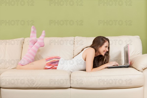 Woman lying on sofa with laptop