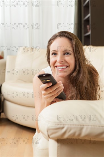 Smiling woman on sofa with remote control