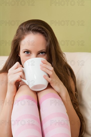 Woman sitting on sofa and holding mug