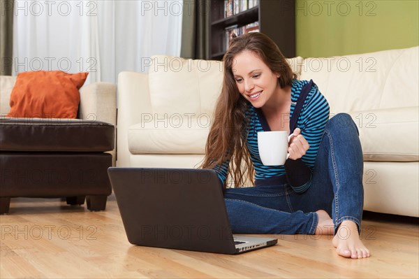 Smiling woman in living room using laptop