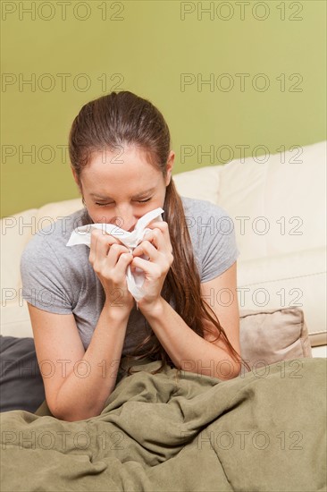Woman on sofa blowing her nose