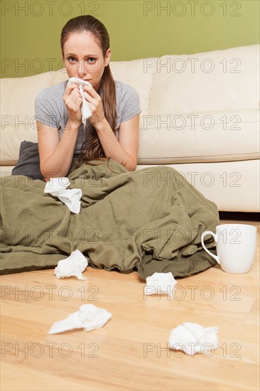 Woman in living room blowing her nose