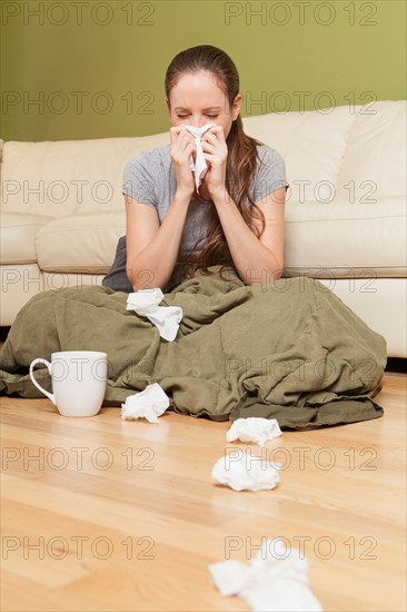 Woman in living room blowing her nose