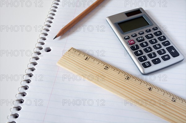 Calculator, ruler and pencil on notebook, studio shot