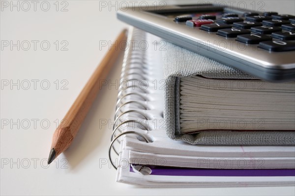 Calculator, textbook and pencil on notebook, studio shot