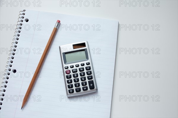 Calculator and pencil on notepad, studio shot