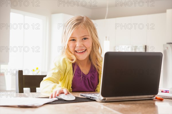 Blonde girl (6-7) using laptop