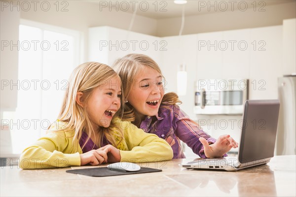 Blonde girls (6-7) using laptop