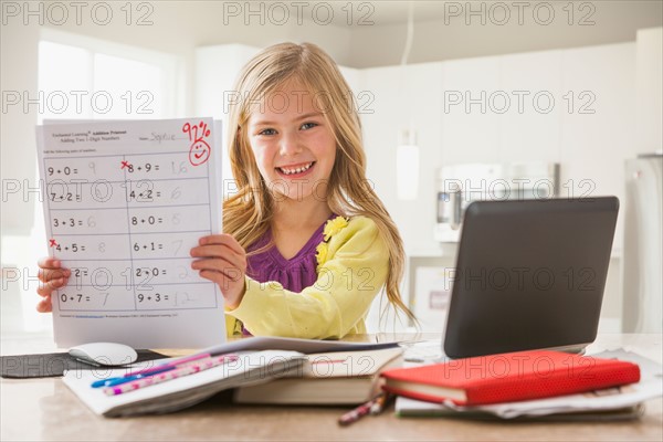 Proud girl (6-7) showing math test