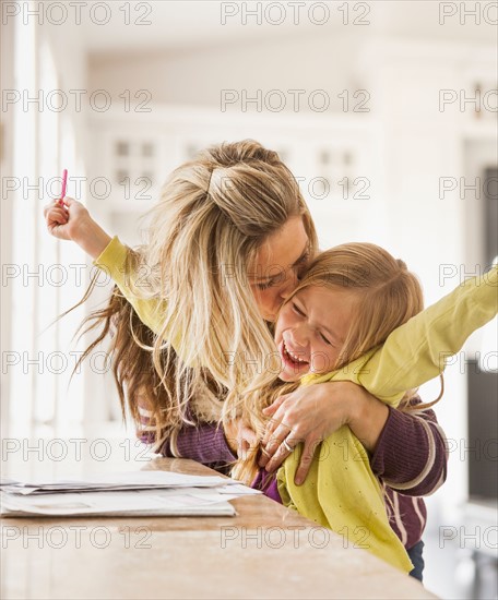 Mother kissing daughter (6-7) during doing homework