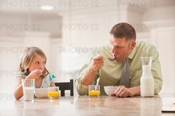 Father and daughter (6-7) eating breakfast