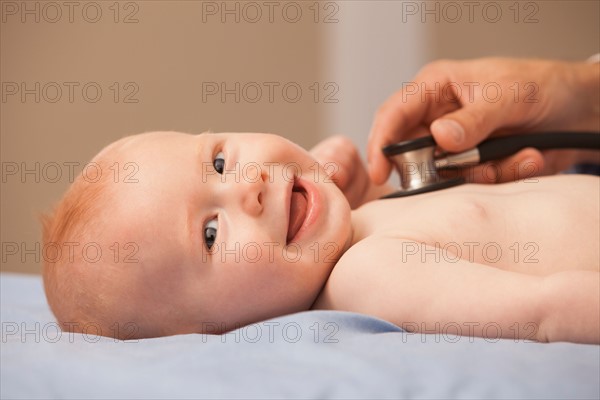 Pediatrician listening heartbeat of baby boy (2-5 months)