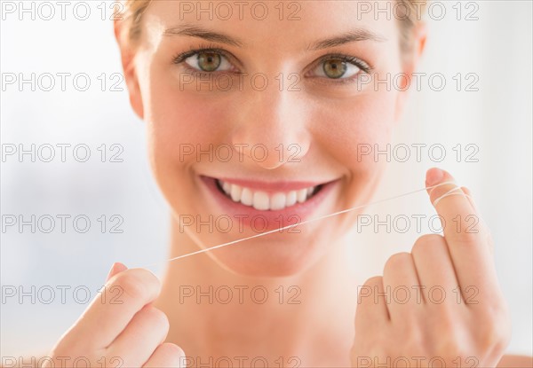 Portrait of woman flossing teeth.