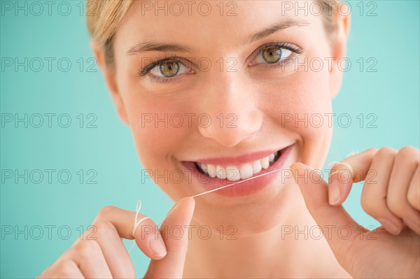 Portrait of woman flossing teeth.