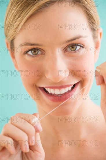 Portrait of woman flossing teeth.