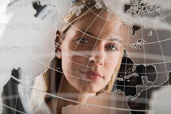 Studio portrait of woman peering through translucent world map.