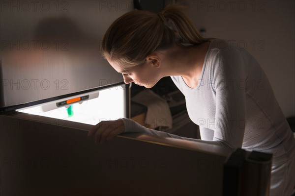 Woman opening fridge at night.