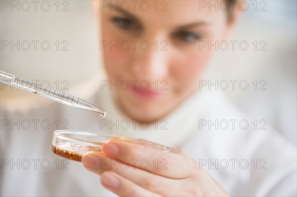 Close-up of scientist using pipette and petri dish.