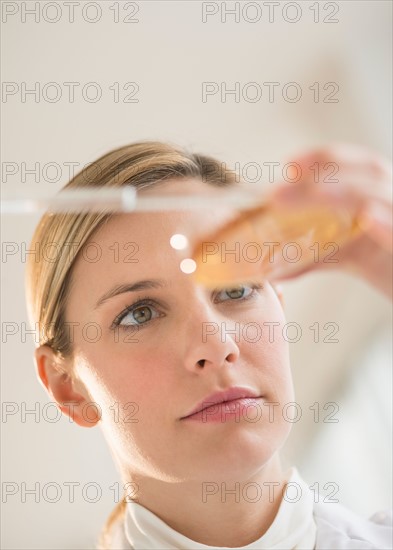 Close-up of scientist using pipette and petri dish.