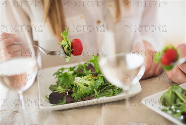 Midsection of woman eating salad.