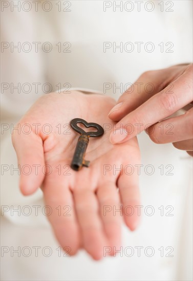 Female hand holding heart-shaped key.