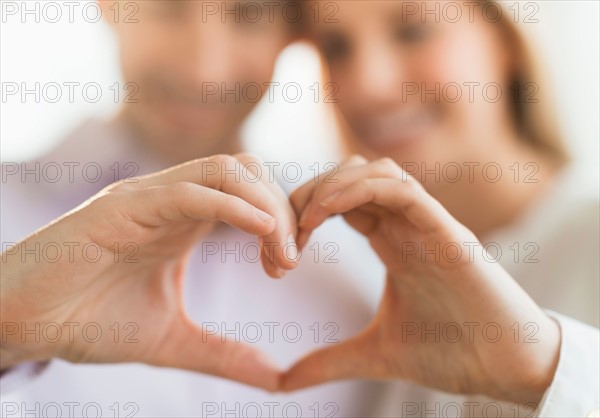 Couple making heart shape with hands.