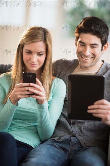 Couple using tablet pc and smartphone.