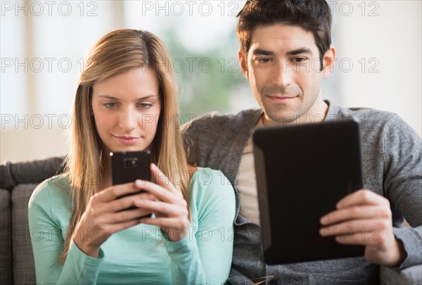 Couple using tablet pc and smartphone.