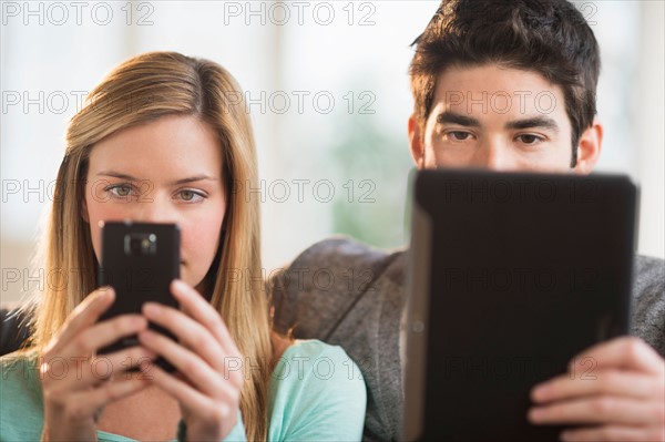 Couple using tablet pc and smartphone.