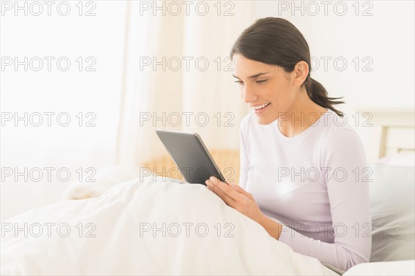 Woman sitting in bed and using digital tablet.