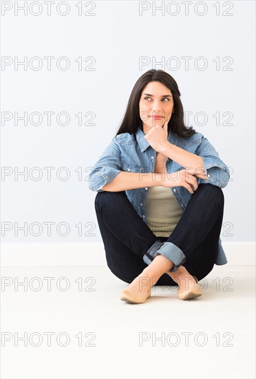 Studio portrait of young woman sitting on floor.