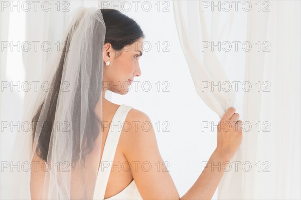 Bride looking through window.