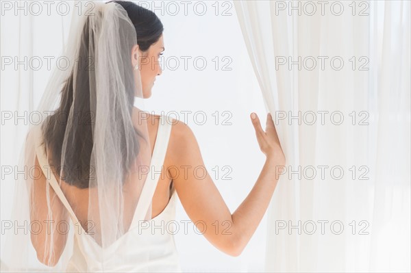 Bride looking through window.