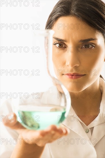 Woman holding beaker with liquid.