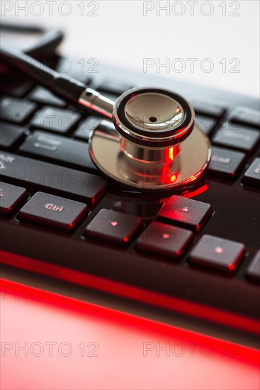 Close up of computer keyboard and stethoscope, studio shot.