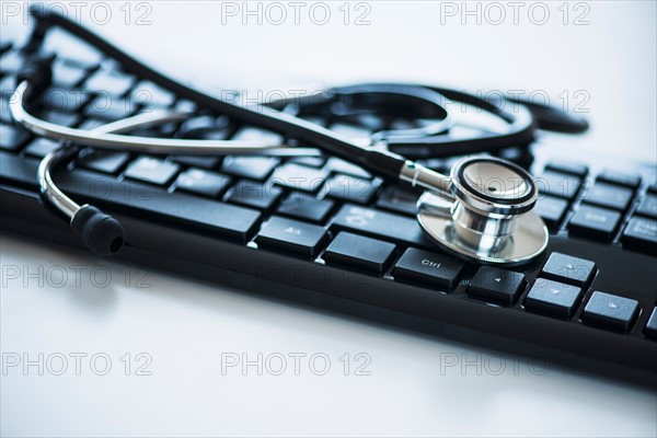 Close up of computer keyboard and stethoscope, studio shot.