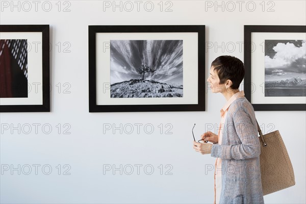 Woman watching photographs in art gallery.