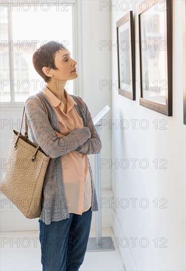 Woman watching photographs in art gallery.