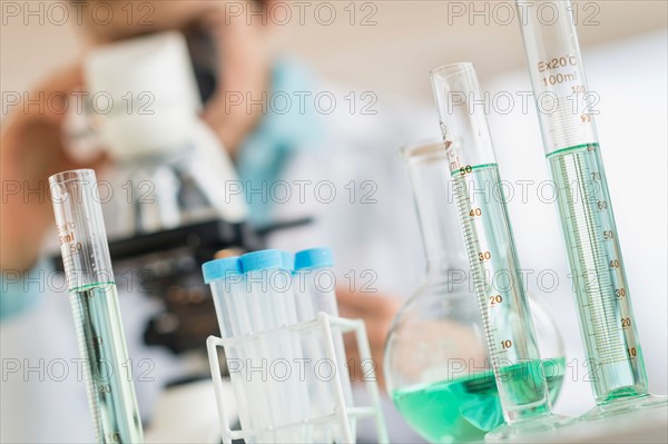 Laboratory glassware with woman in background.