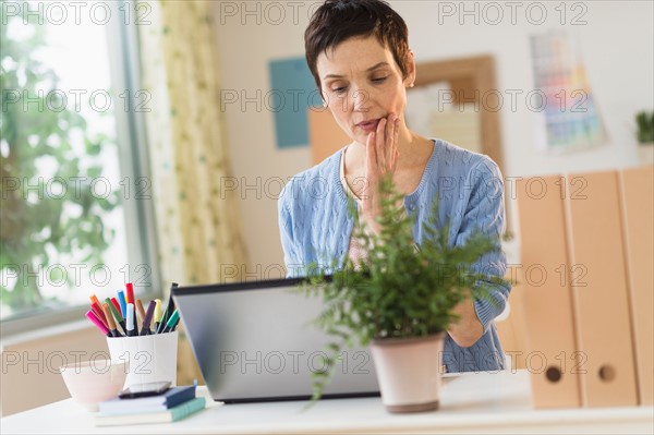 Woman using laptop in home office.