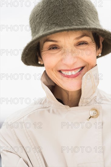 Portrait of smiling woman wearing raincoat and hat.