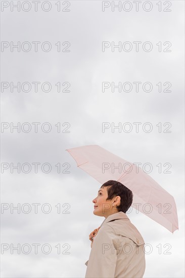 Woman wearing raincoat and holding umbrella.