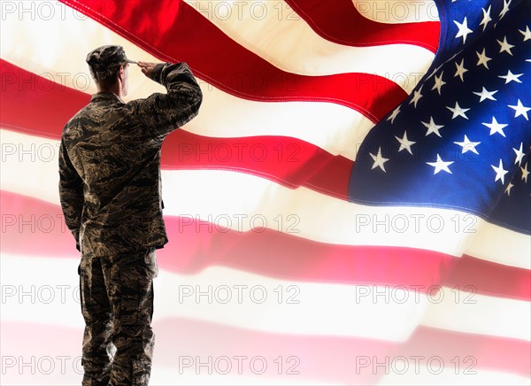 Army soldier saluting in front of American flag.