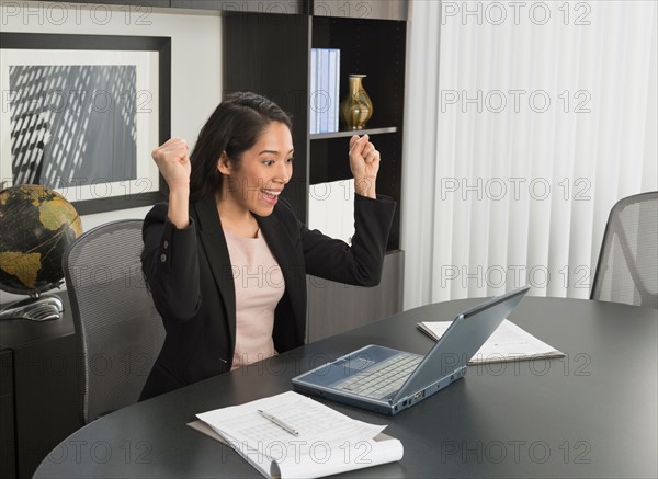 Businesswoman expressing happiness at desk.