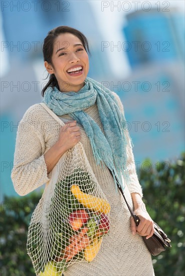 Portrait of smiling young woman with grocery shopping bag.