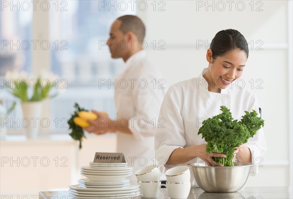 Couple during preparations in kitchen of their own restaurant.