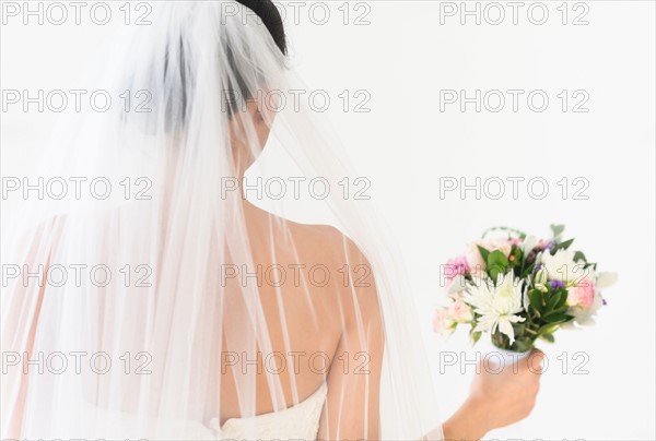 Portrait of bride in veil holding bouquet.