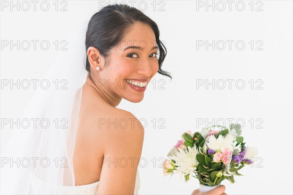 Portrait of bride in veil holding bouquet.