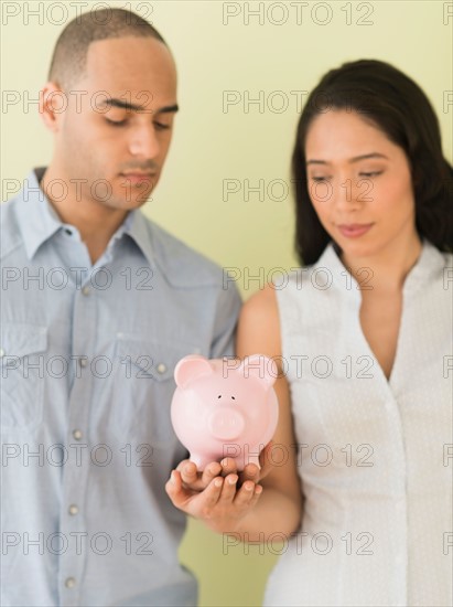 Young couple holding piggy bank.