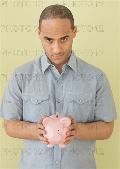 Young man holding piggy bank.